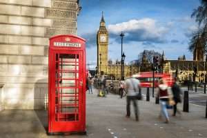 Red phone box with Big Ben, with people waling on the streets of London.