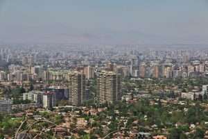 Skyline of Santiago, Chile on a sunny day. behind the buildings, haze or smog somewhat obscures rolling hills.