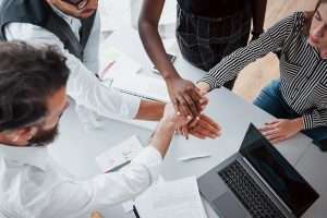 Young business people discussing joining their hands as a team during meeting in an office.